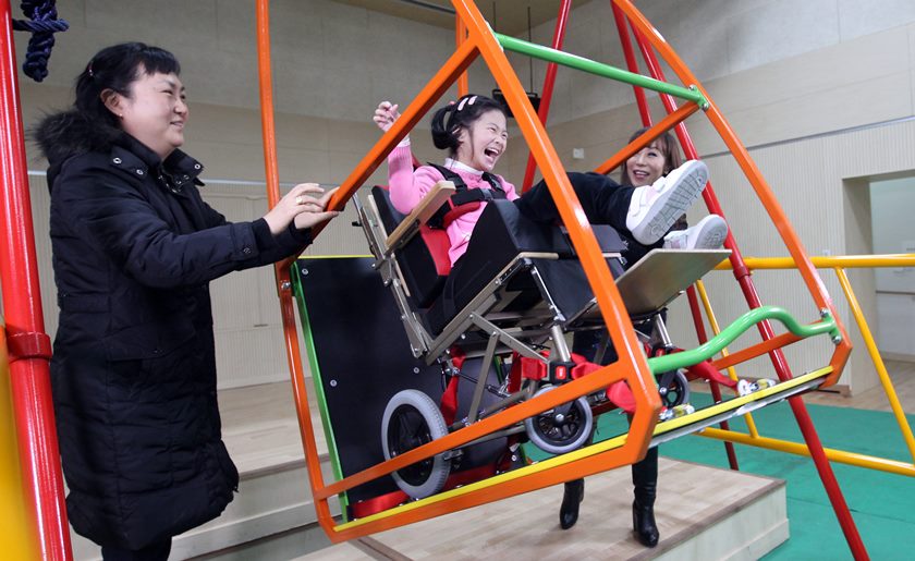 휠체어를 탄 어린이가 성악가 조수미(맨 오른쪽)씨가 기증한 휠체어 그네를 타고 있다. /조선DB