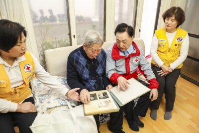 미상봉 이산가족인 이광진 씨가 헤어진 동생들의 사진을 김철수 대한적십자사 회장에게 보여주며 담소를 나누고 있다. /대한적십자사